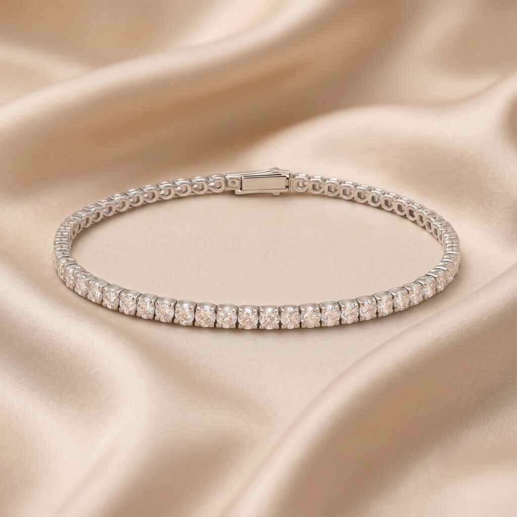 Nahaufnahme eines eleganten Weißgold-Tennisarmbands, besetzt mit einer durchgehenden Reihe runder, champagnerfarbener Diamanten. Das Armband ist in einer Ovalform auf einem drapierten, champagnerfarbenen Satinstoff arrangiert. Der Verschluss ist oben sichtbar.