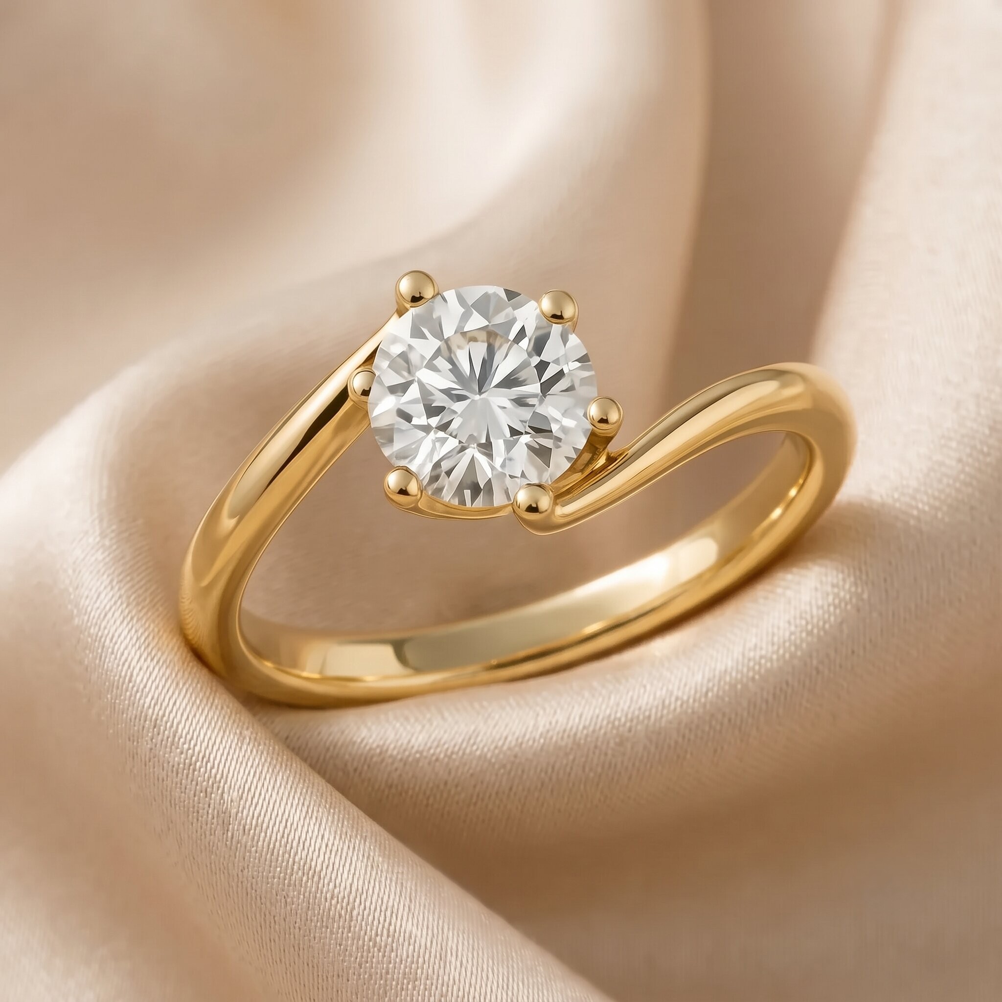 Nahaufnahme eines Solitär-Diamantrings aus poliertem Gelbgold mit einem einzigartigen, asymmetrischen Bypass-Schaft. Ein großer, runder Brillant-Diamant (oder ähnlicher facettierter Stein) ist in einer Vier-Krappen-Fassung gefasst. Der Ring ruht auf einem weichen, drapierten Champagner-Satin-Hintergrund, der weiches Licht reflektiert.